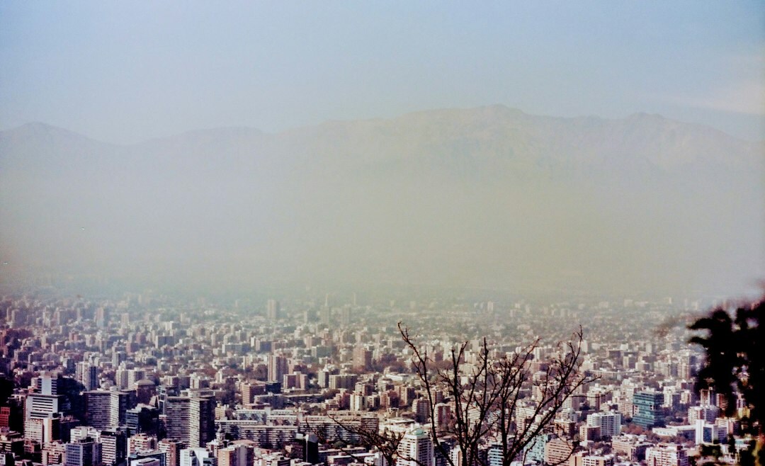 Documentary photograph of a busy street in Santiago Chile with pedestrians and mountains in the background